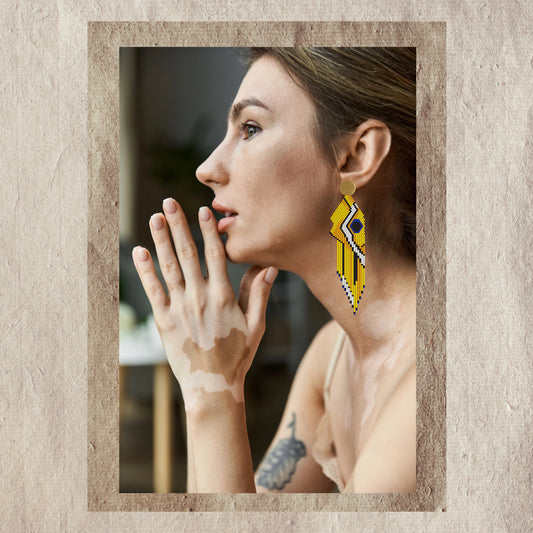 Woman wearing yellow fish earrings with a neutral background