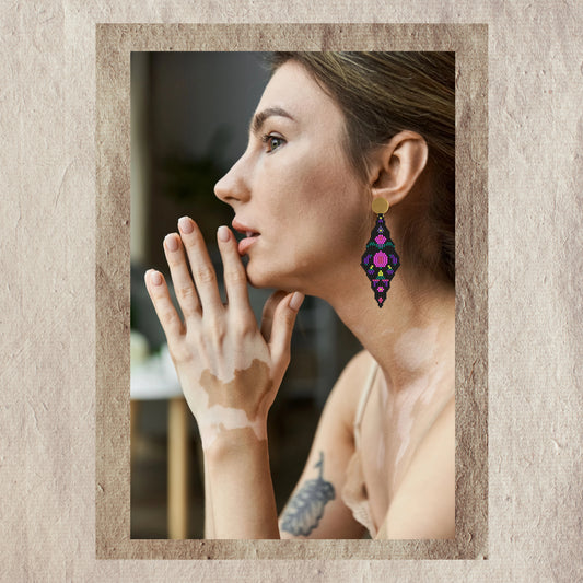 Woman wearing colorful fuchsia earrings with a neutral background