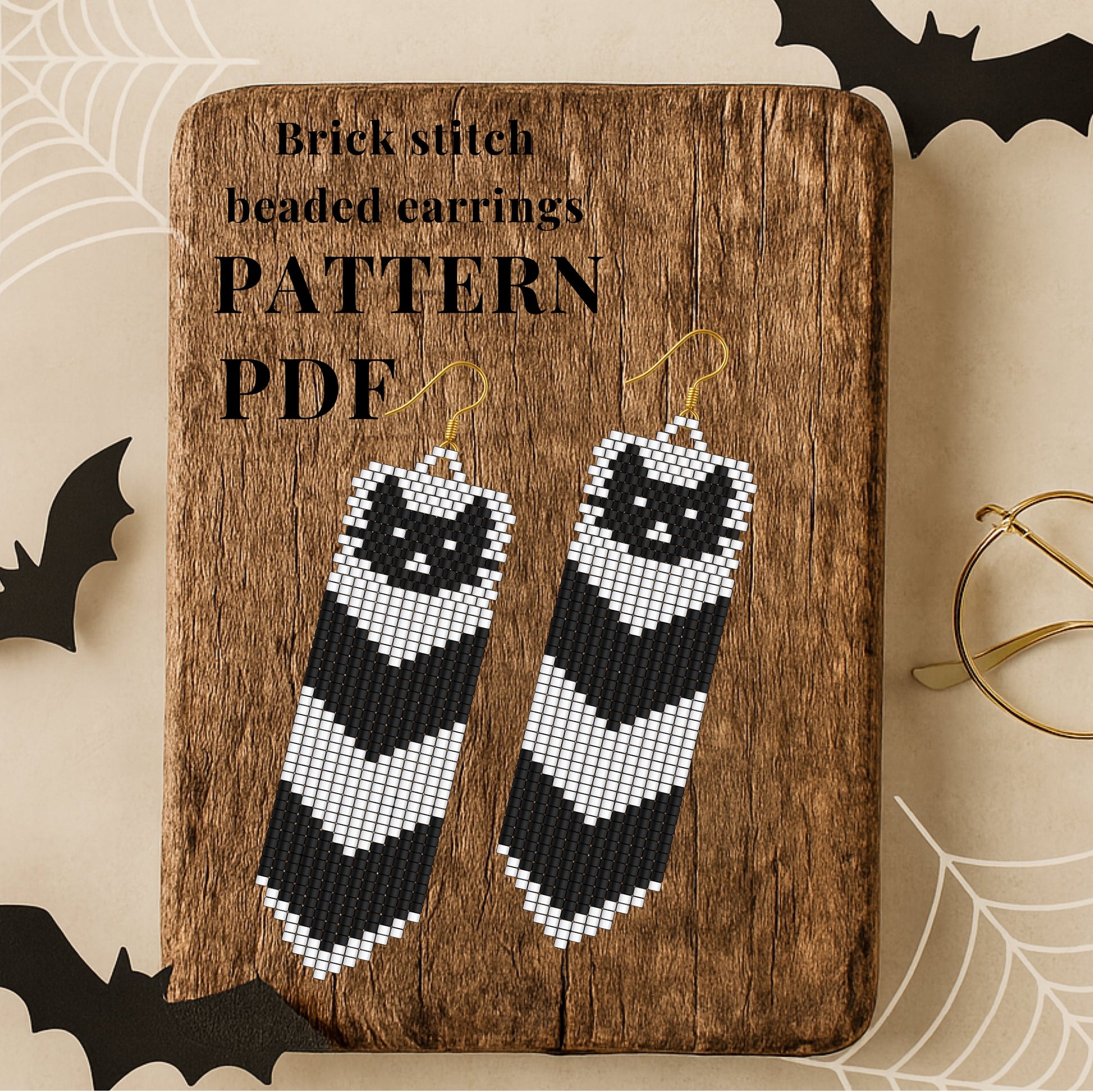 Brick stitch beaded cat earrings on a wooden board with text about a pattern PDF, surrounded by Halloween decorations.