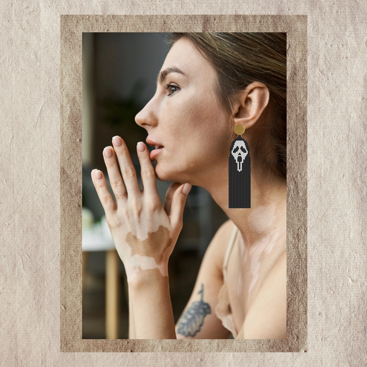 Woman wearing a scream face  earring with a neutral background