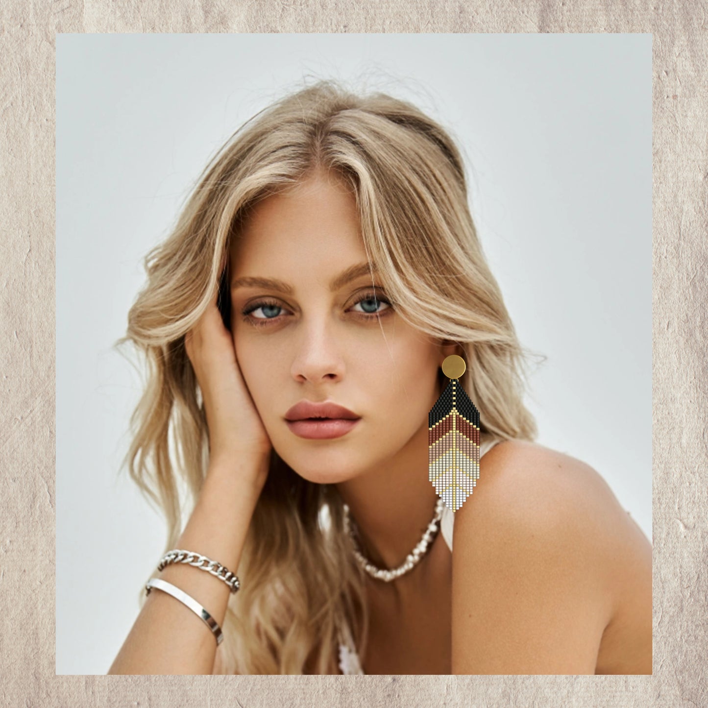 Woman wearing gold feather earrings on neutral background
