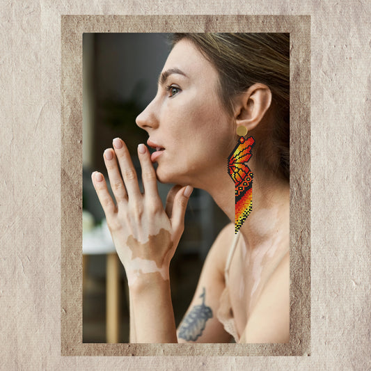Woman wearing colorful butterfly wings earrings with a neutral background